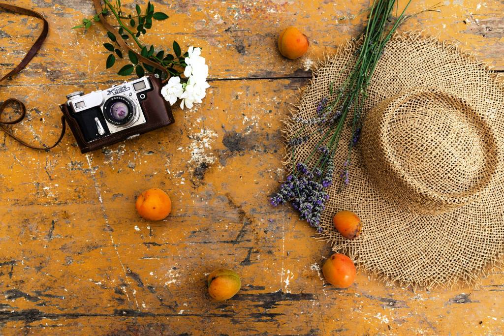 flatlay-photo-of-flowers-camera-apricots-a-hat-on-the-wooden-table